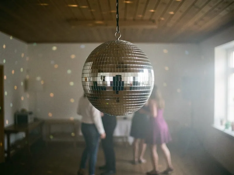 Diskokugle over dansegulvet, der kaster lyspletter på væggene i en sal med let røg