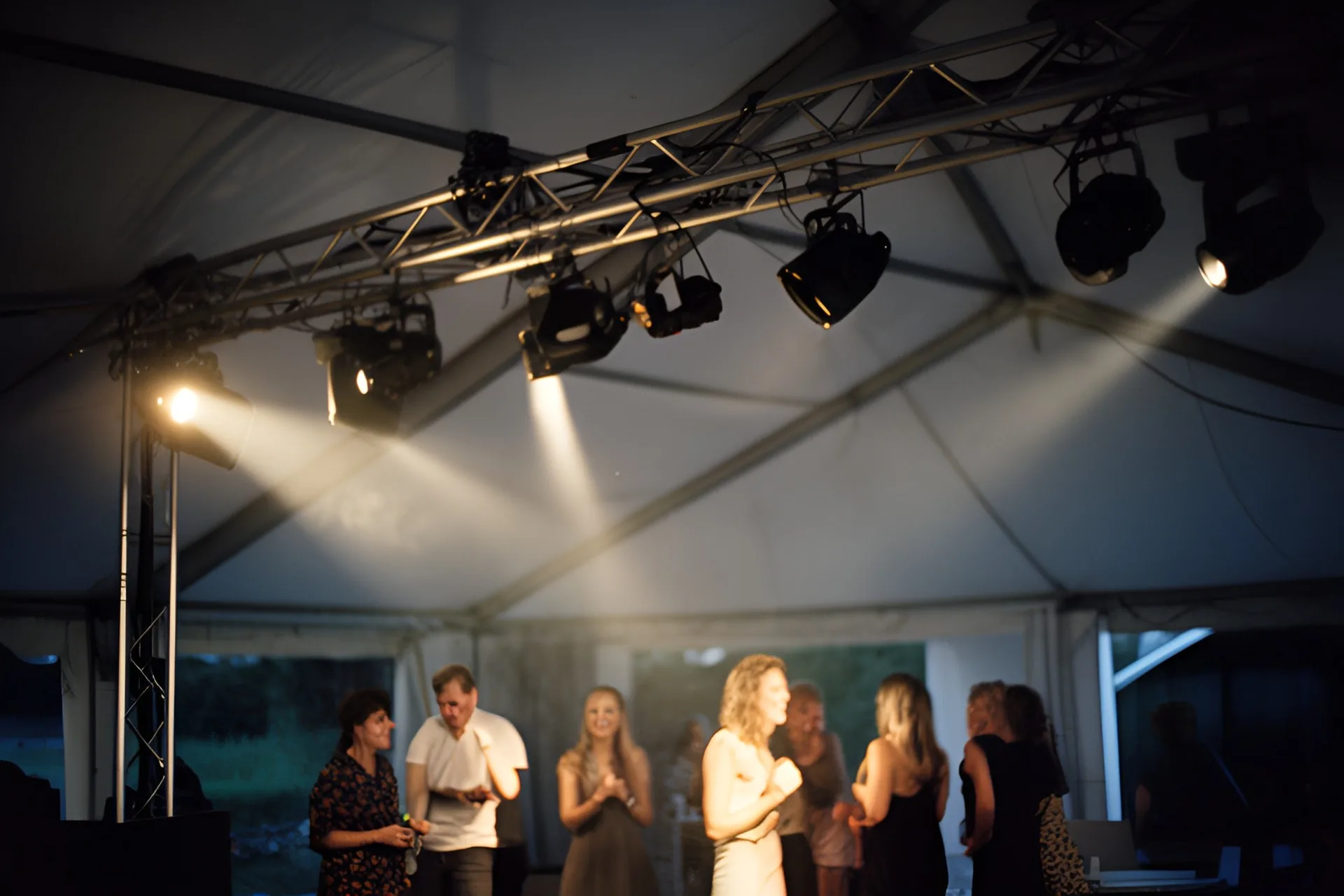 Lysrig med spots over et dansegulv i et festtelt om aftenen